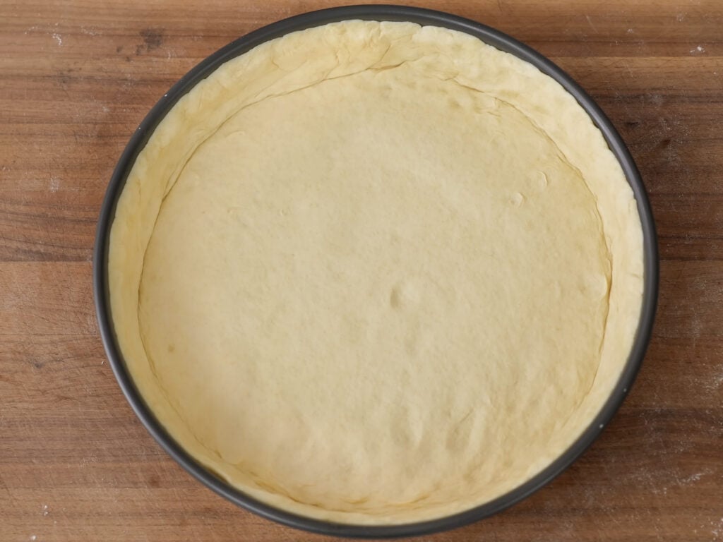 deep dish pizza dough formed into a round pan