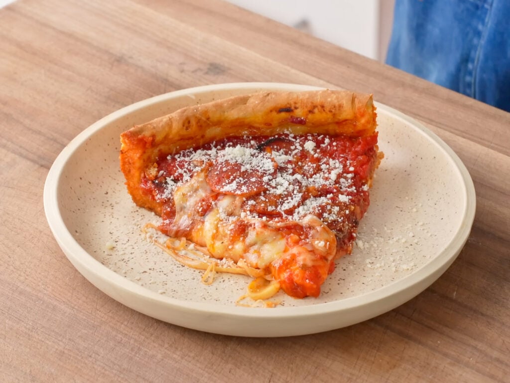 deep dish pizza slice on beige plate