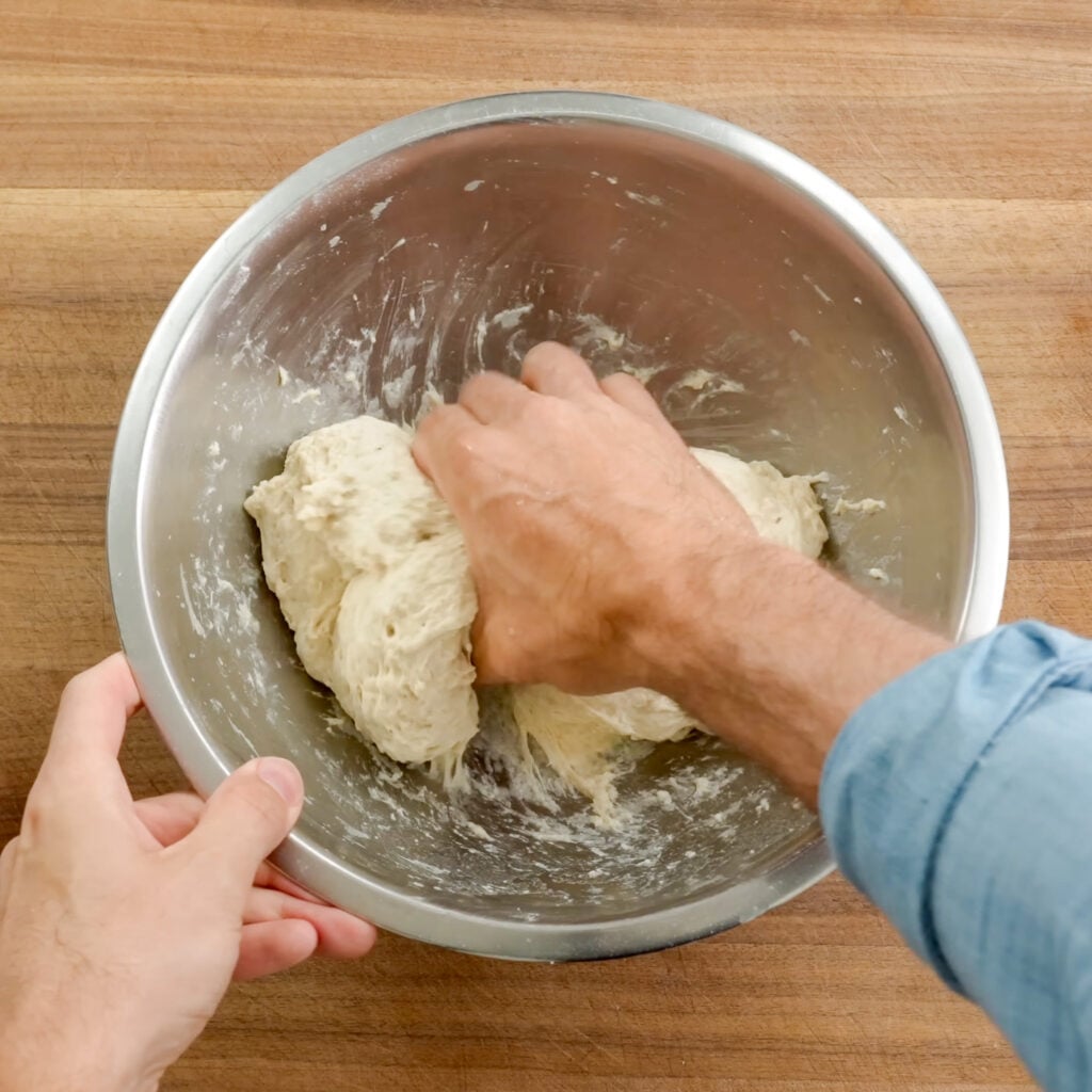 squeezing dough by hand in silver bowl