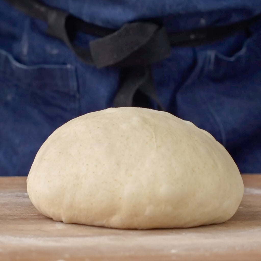folded and founded bread dough on wood cutting board