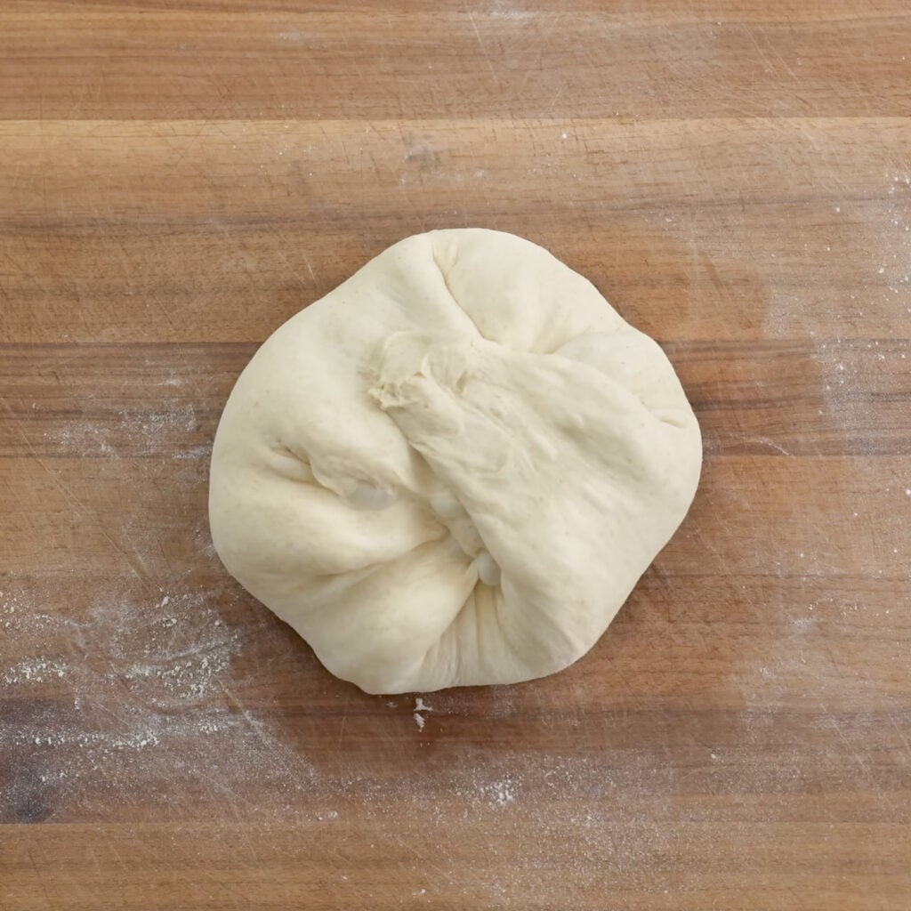 folded bread dough on wood cutting board