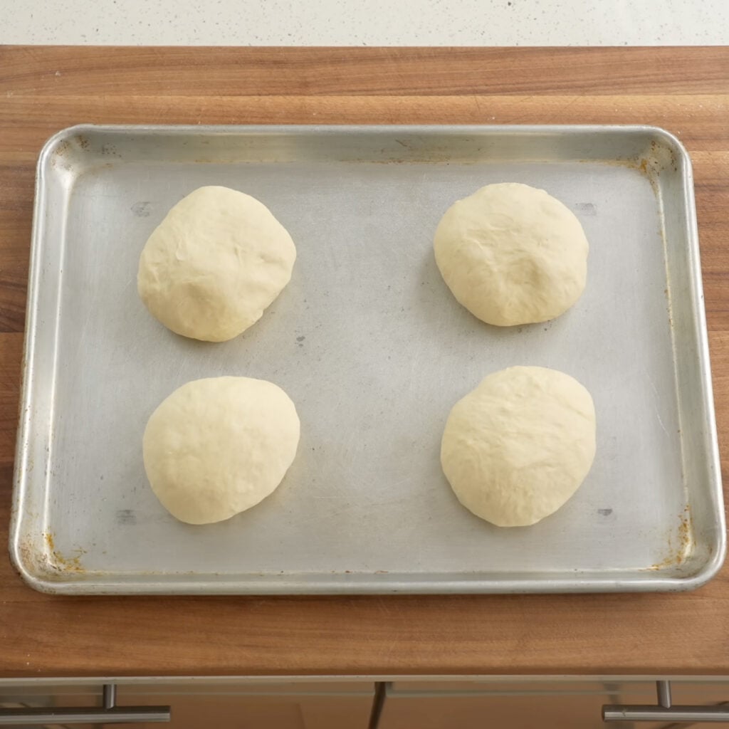 4 balls of dough on silver half sheet tray