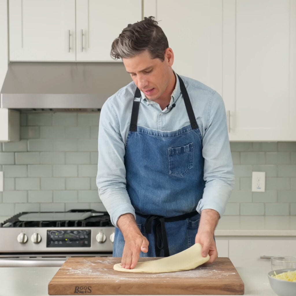 Brian lagerstrom blue apron hand stretching pizza dough on wood cutting board