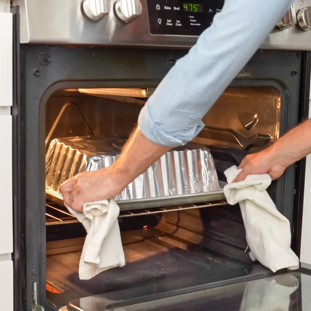 hands removing foil pan from oven