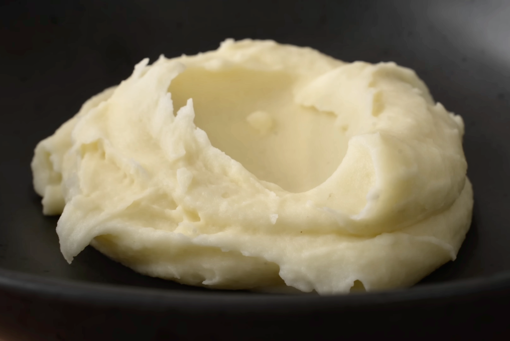 silky potato puree in black bowl