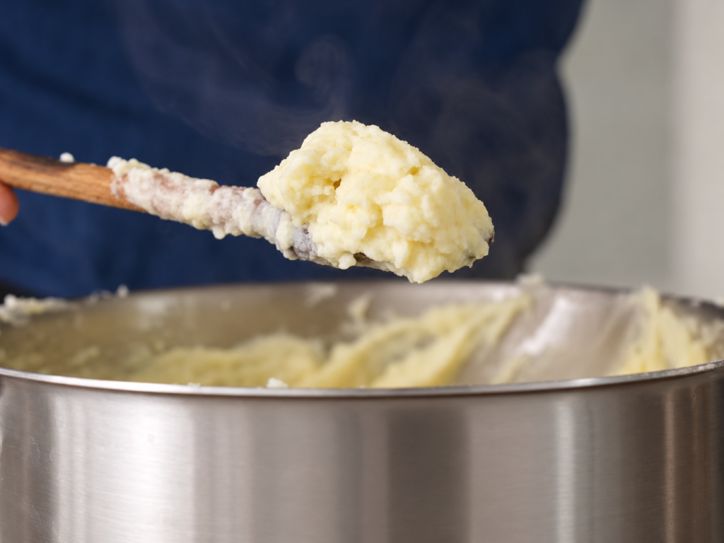 wooden spoon holding up mashed potatoes