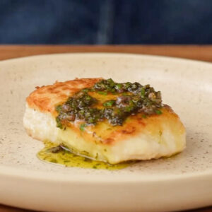piece of white fish with brown butter caper sauce on a beige plate