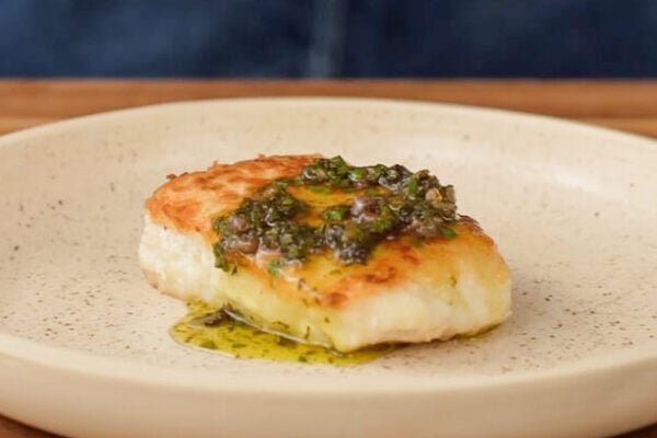 piece of white fish with brown butter caper sauce on a beige plate