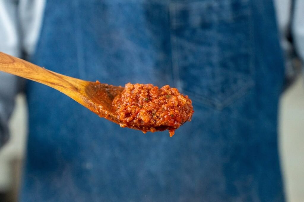 wooden spoon lifting up red eat sauce