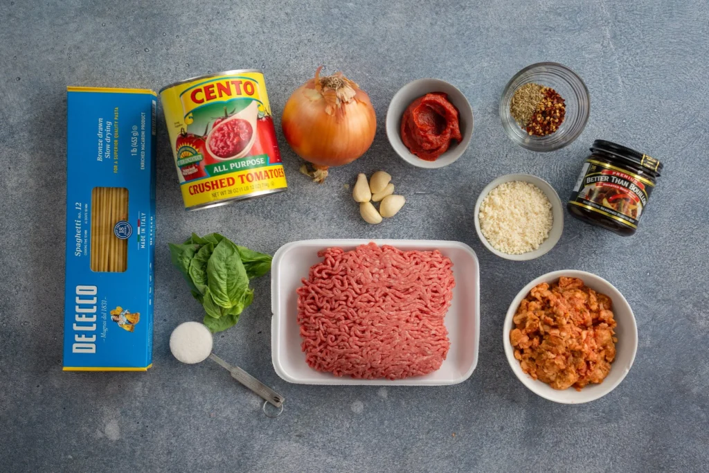 spaghetti and meat sauce ingredients on a grey concrete background