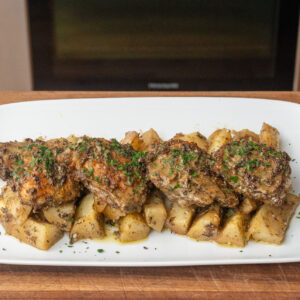 greek chicken and potatoes on a white platter