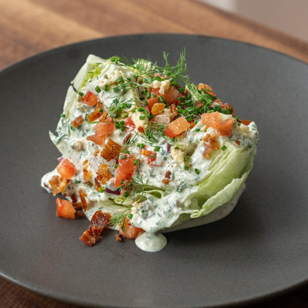 dressed wedge salad on black plate
