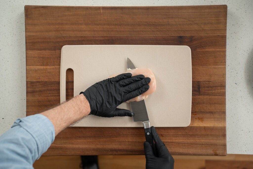 chef butterflying chicken breast on cutting board