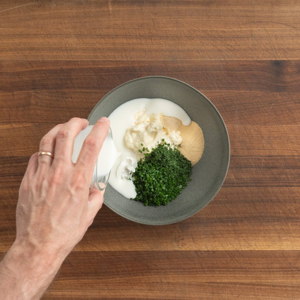 adding ingredients into a bowl for blue cheese dressing