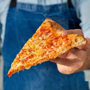 slice of cheese pizza in front of blue apron