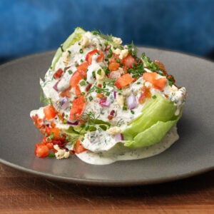 classic wedge salad with tomato blue cheese and bacon on a grey plate