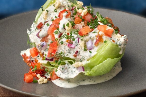 classic wedge salad with tomato blue cheese and bacon on a grey plate