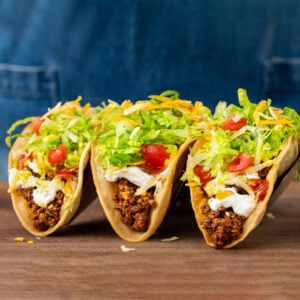 hard shell ground beef tacos with sour cream tomato lettuce and cheese