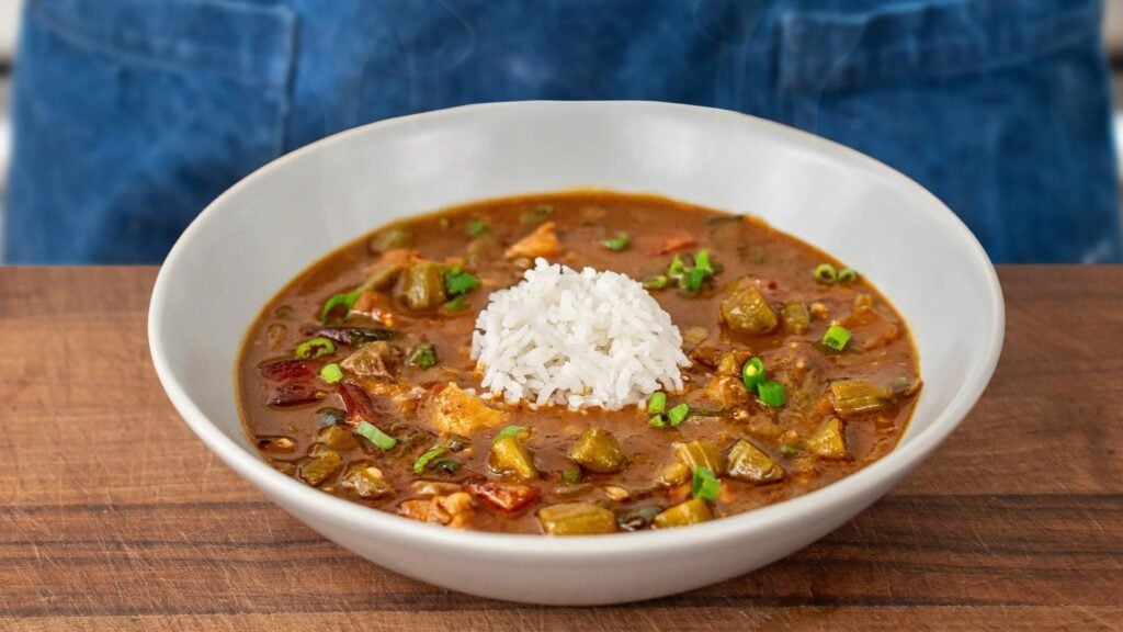 cajun gumbo in a grey bowl topped with a mound of white rice