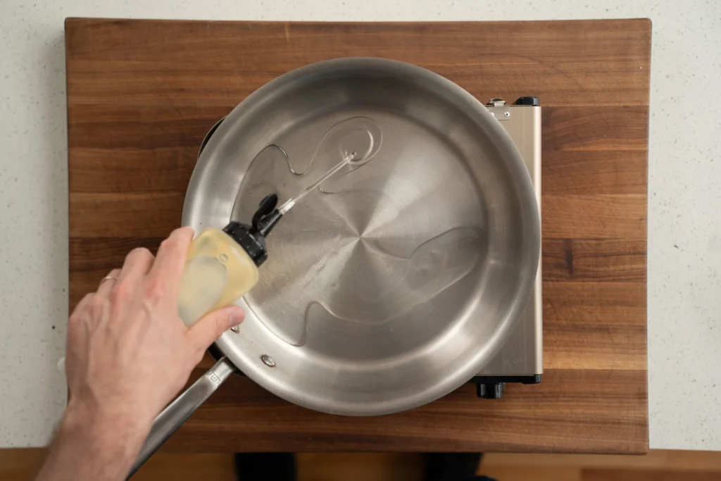 adding oil to saute pan