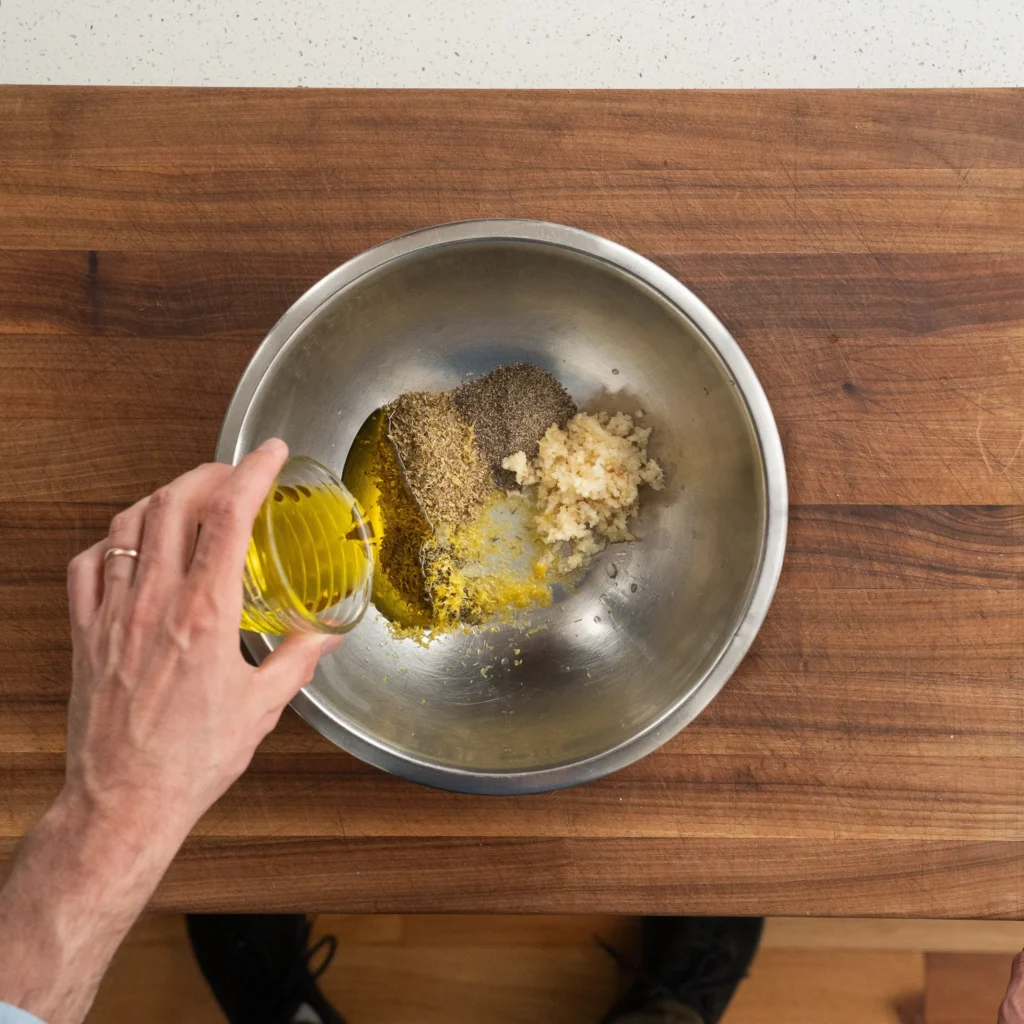 adding oil to spices in silver metal bowl on cutting board