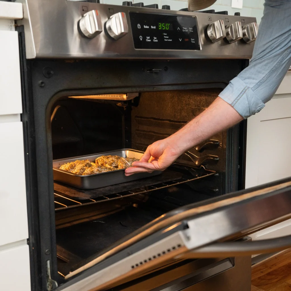 placing pan of chicken and potatoes in an oven at 350