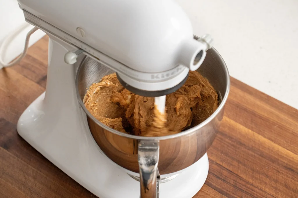 white kitchen aid stand mixer spinning peanut butter cookie dough