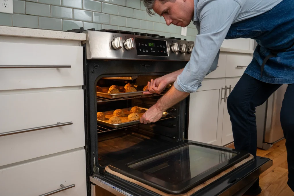 Brian Lagerstrom placing 2 sheet pans of peanut butter cookies in an oven