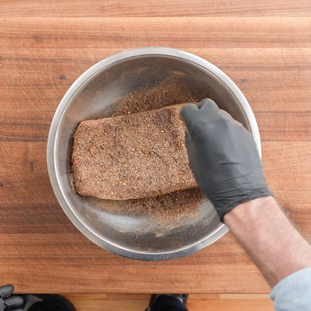 rubbing pastrami spices on corned beef