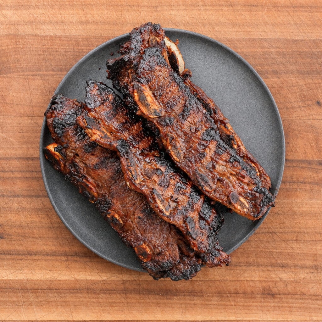 a stack of grilled korean short ribs on a black plate