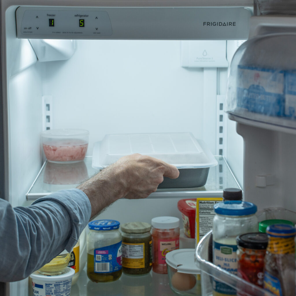 placing a pan of korean short ribs in the refrigerator