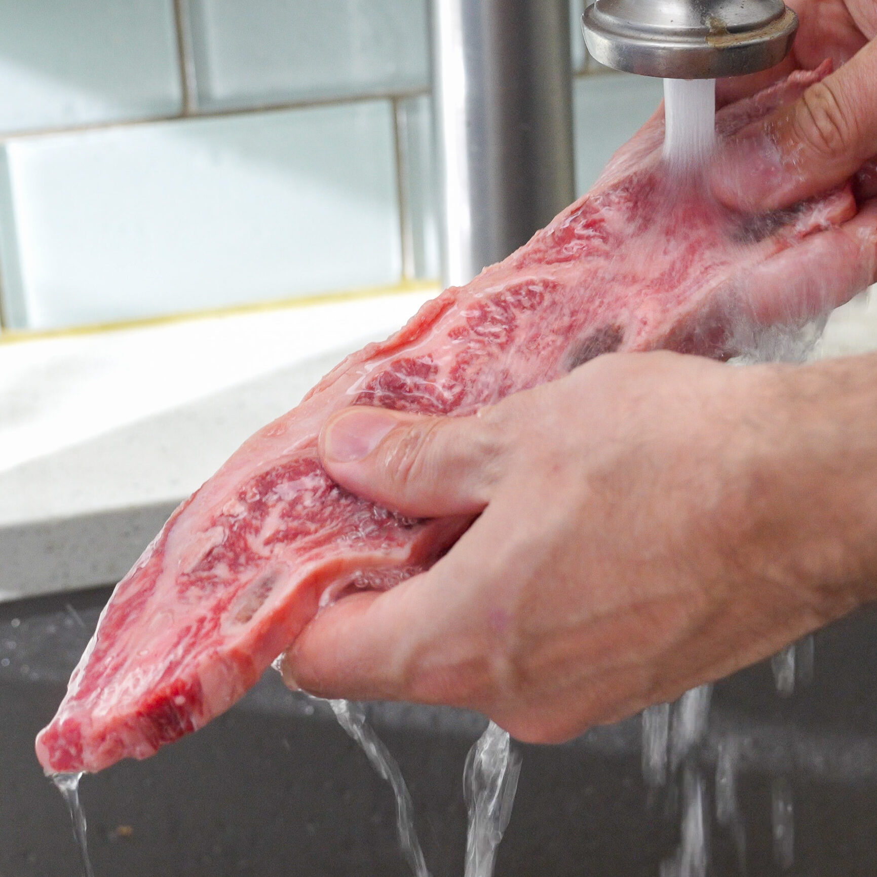 rinsing flanken cut short rib under water to remove bone dust