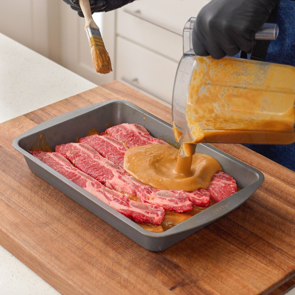 pouring marinade over korean short ribs
