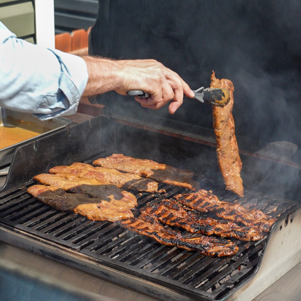 korean short ribs with grill marks being flipped with tongs