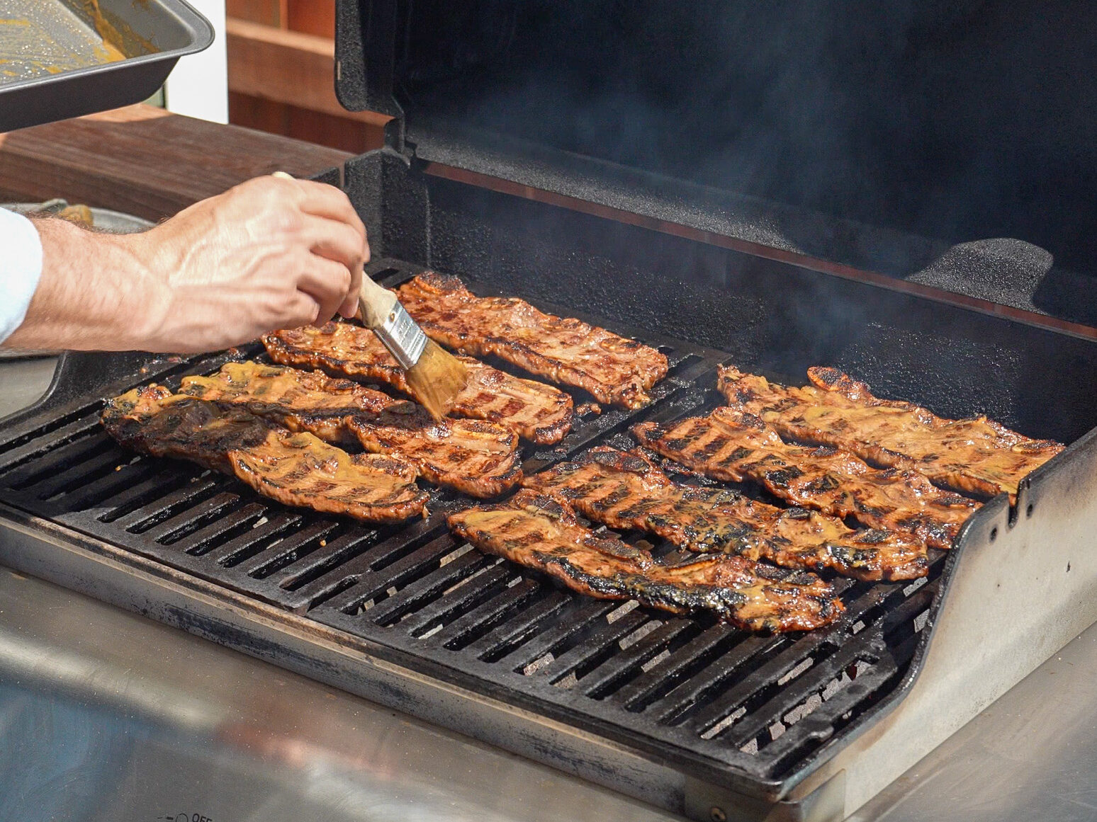 brushing additional marinade on korean short ribs on a grill