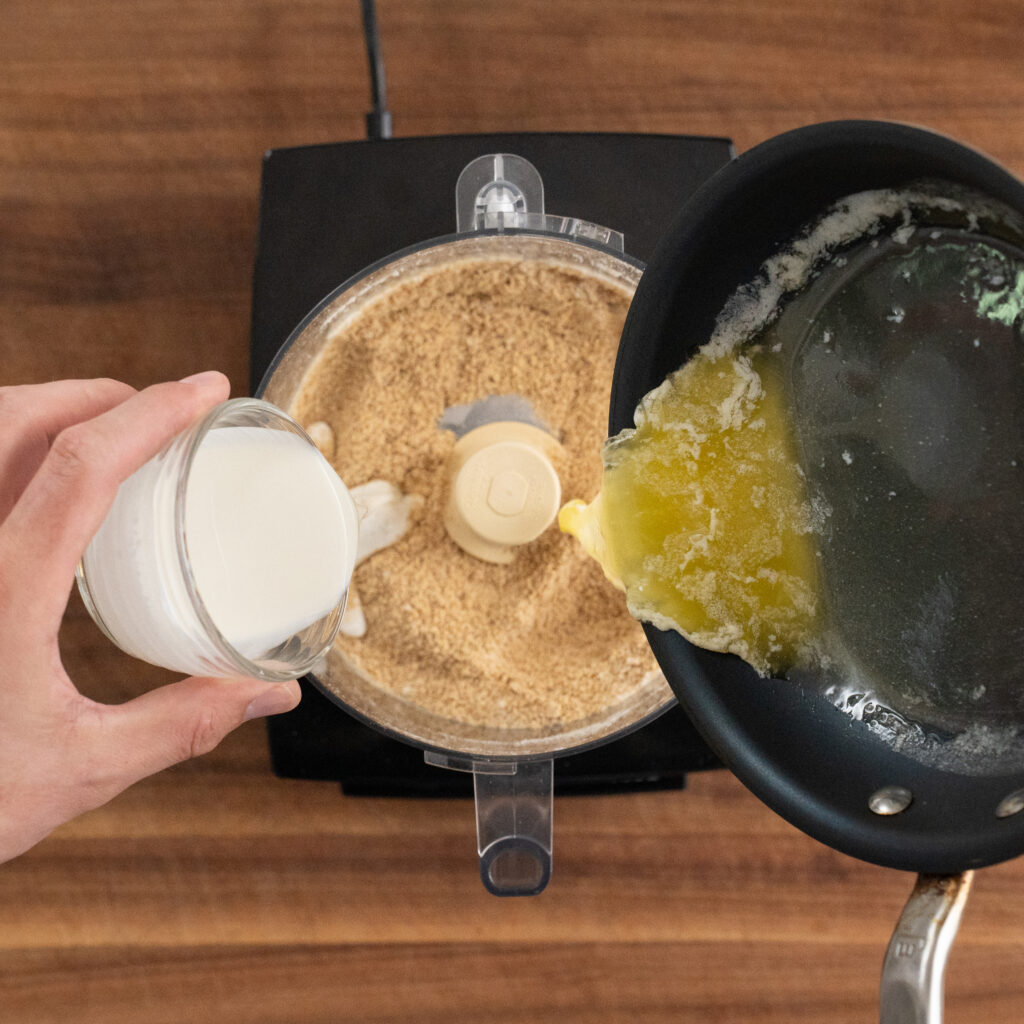 adding cream and melted butter to graham crackers in food processor