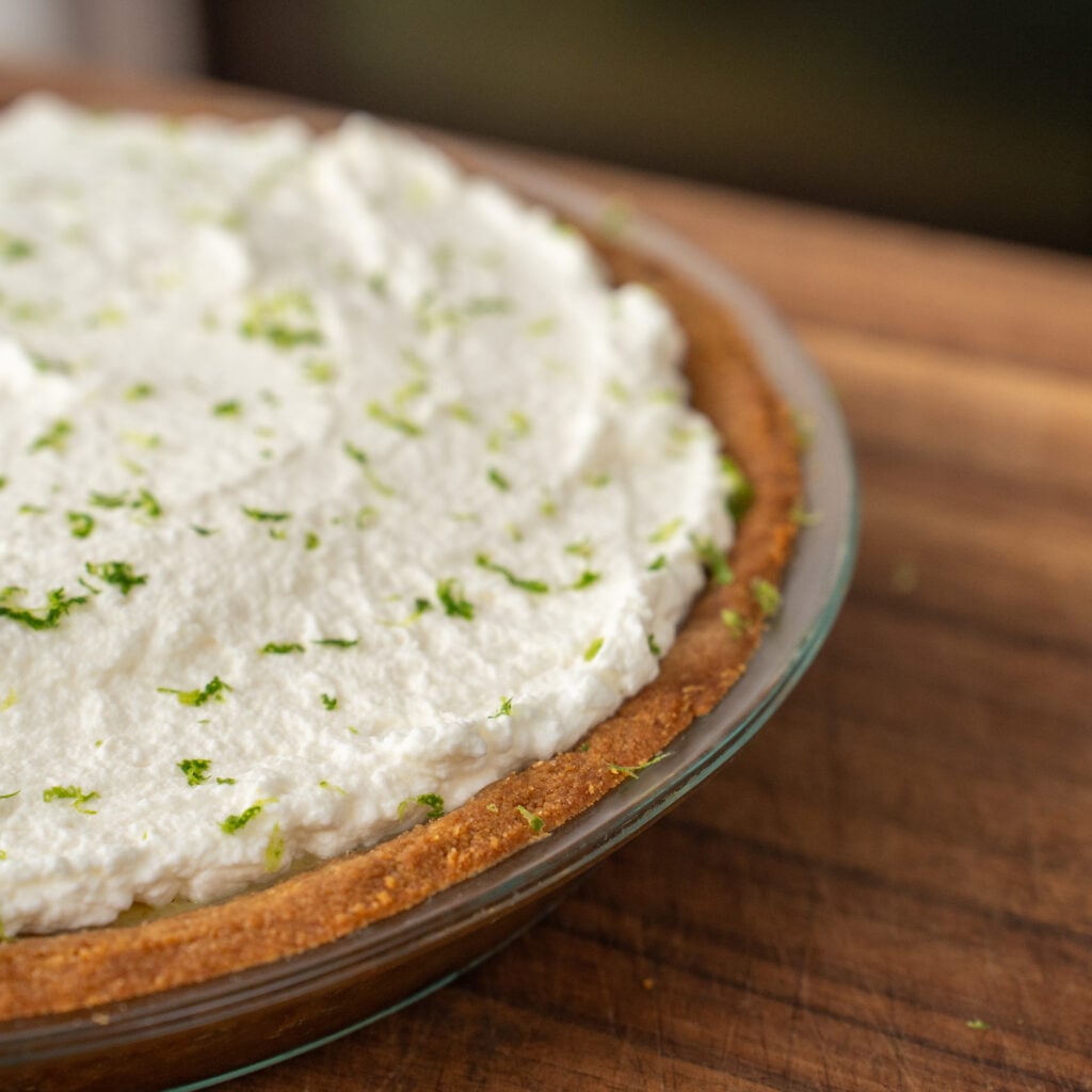 close up of key lime pie topped with lime zest in pie plate
