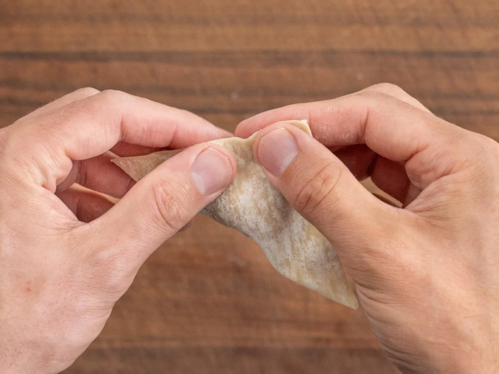 hands pinching edges of wonton wrapper to seal