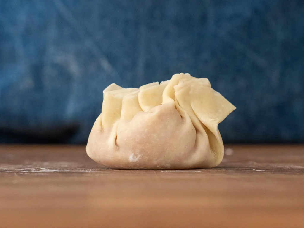 folded wonton sitting on wooden cutting board