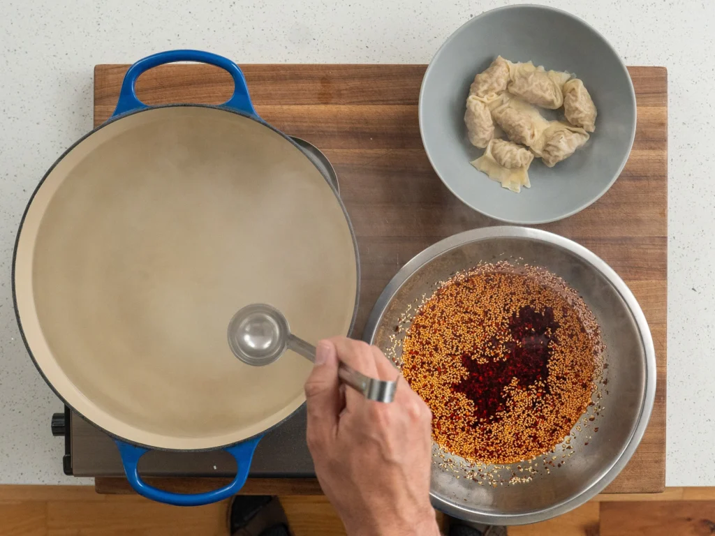 small ladle scooping out wonton poaching liquid