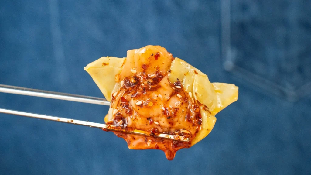 chopsticks holding a chili oil coated wonton