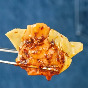 chopsticks holding chili oil glazed wonton