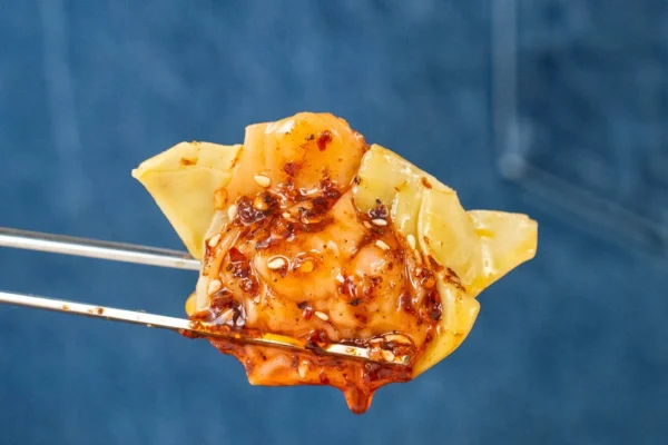 chopsticks holding chili oil glazed wonton