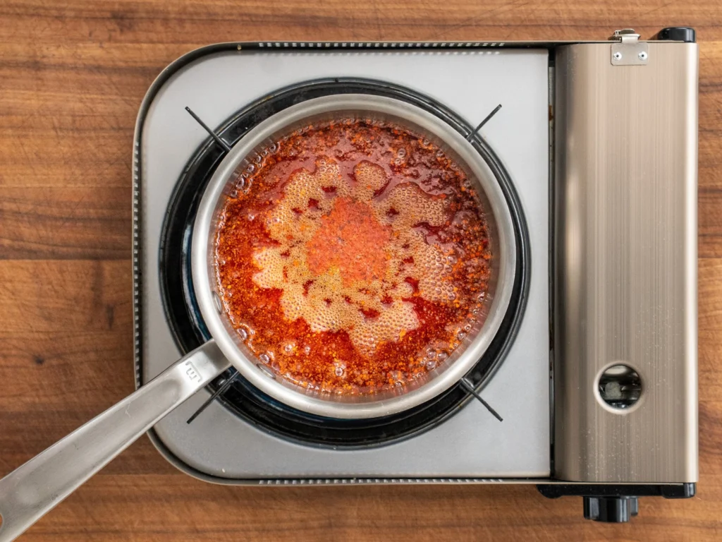 red gochugaru spice and oil simmering in a a sauce pan