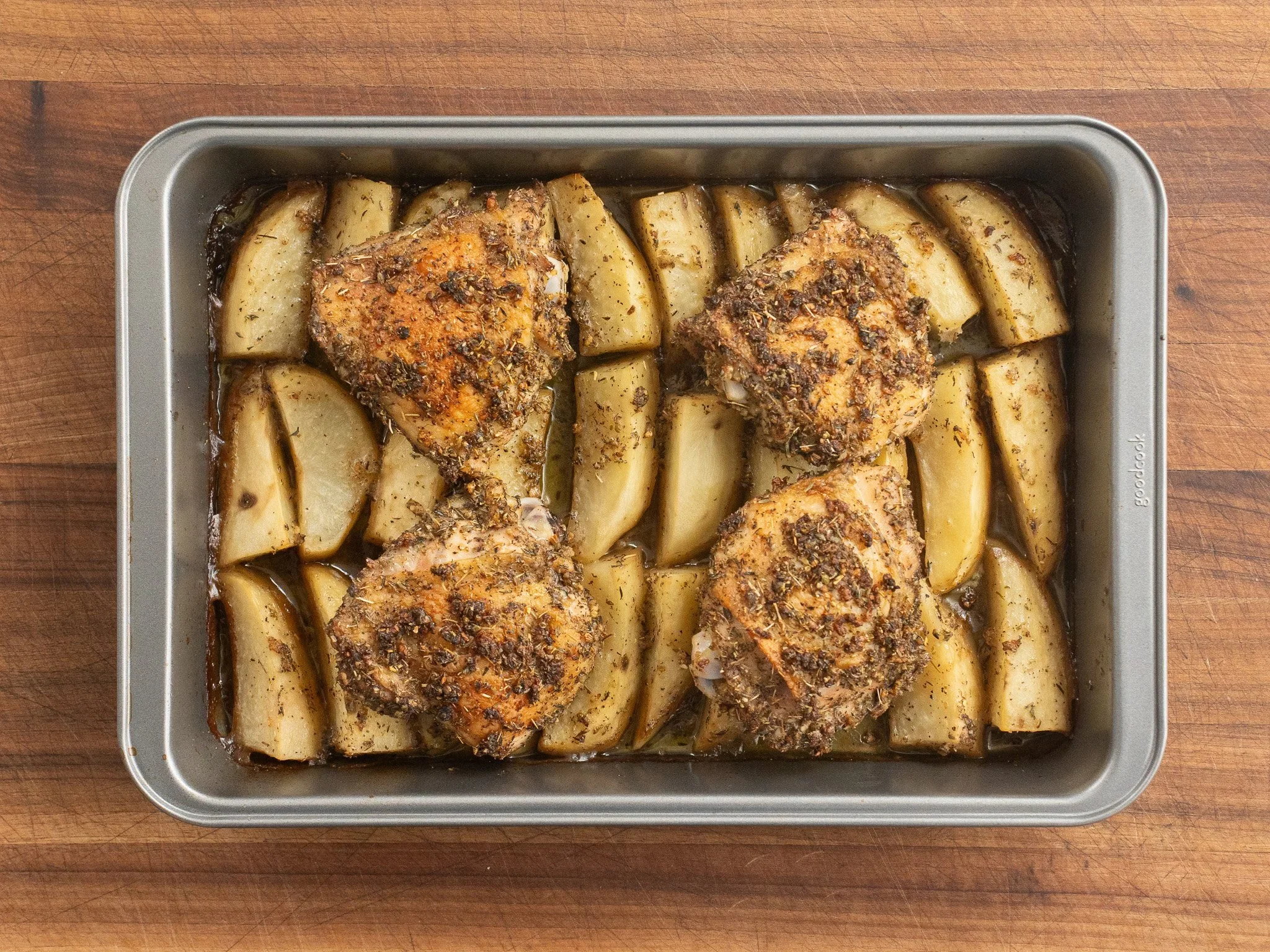 greek roast chicken thighs and potatoes in a metal pan