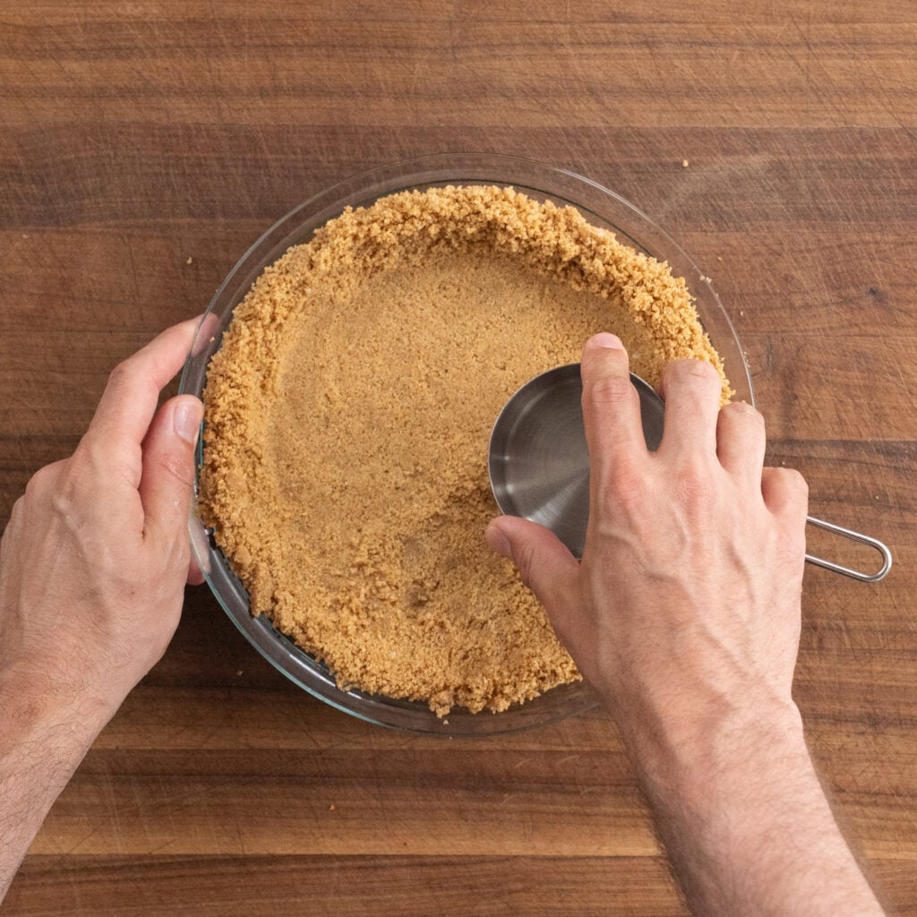 even out graham cracker crust in pie plate with measuring cup