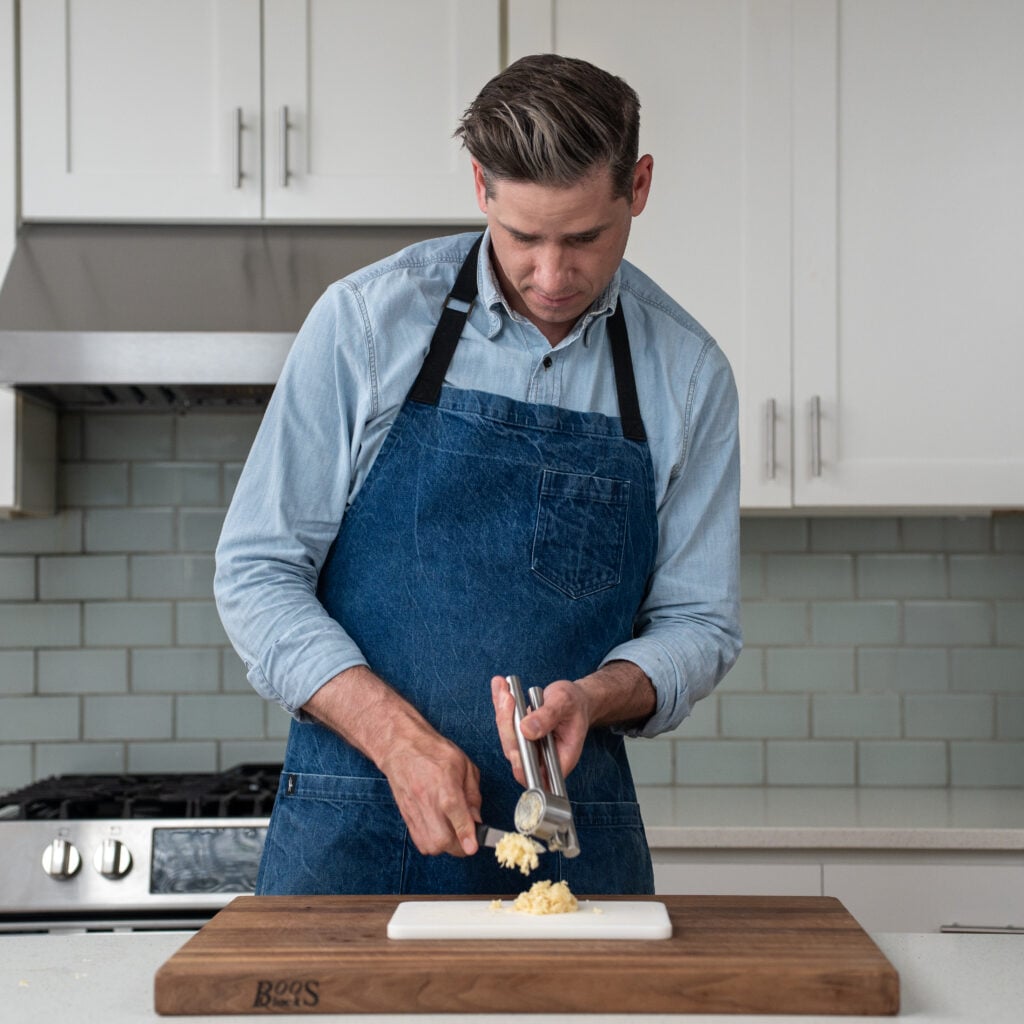 man using garlic press to mince garlic