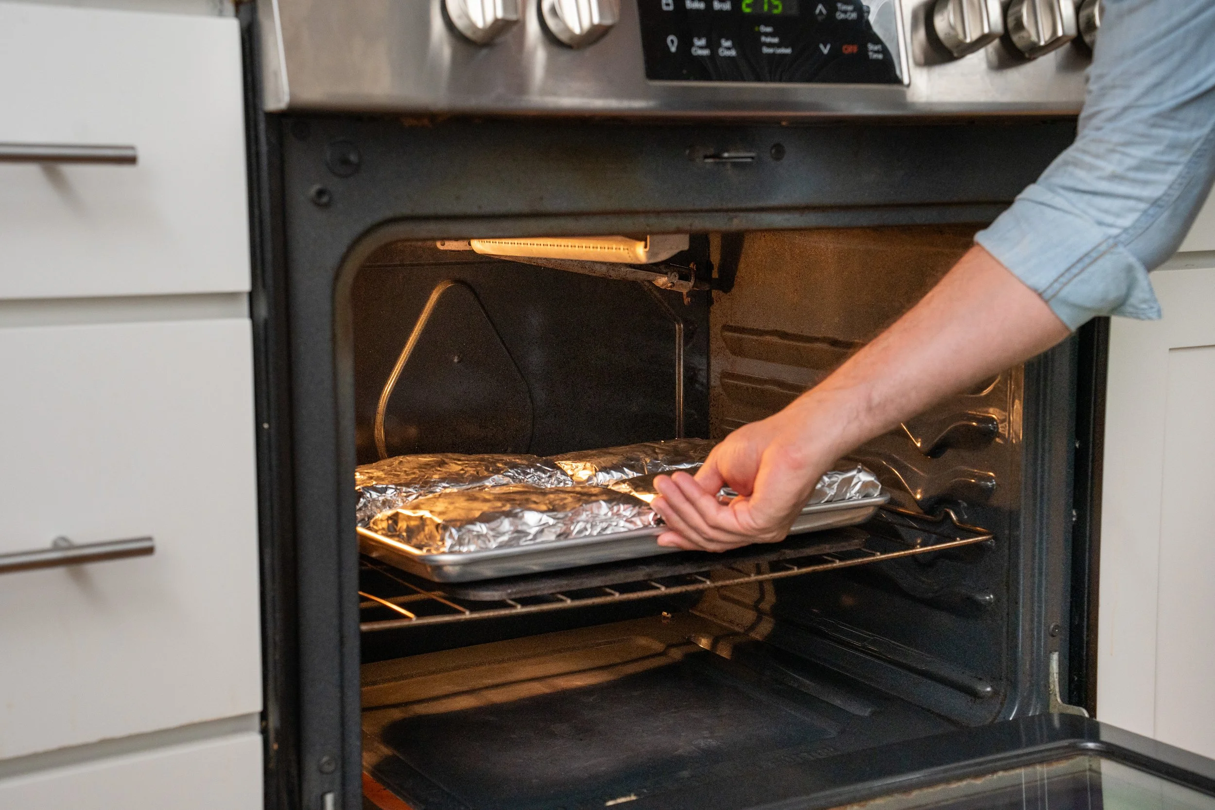 placing tray of foil wrapped ribs in oven