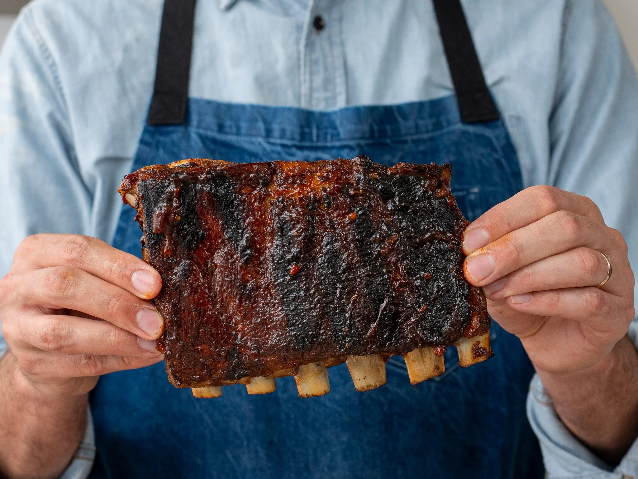 man holding half rack grilled bbq ribs