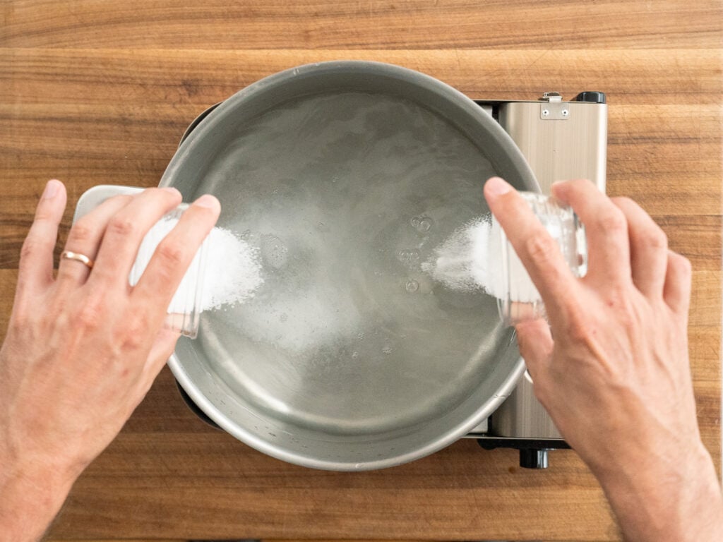 pouring salt and sugar into pot of boiling water